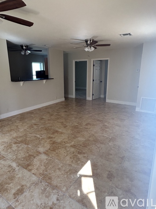 A spacious room with a ceiling fan and a flat screen TV mounted on the wall.
