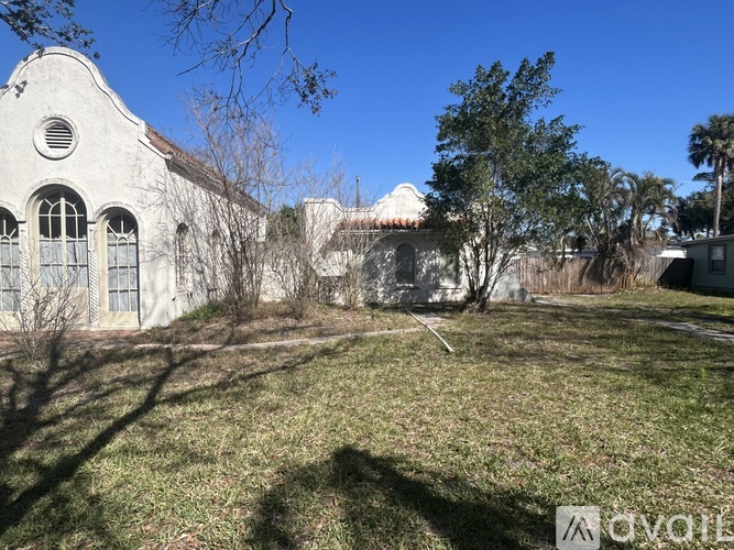 A white building with a circular window is surrounded by a grassy area.