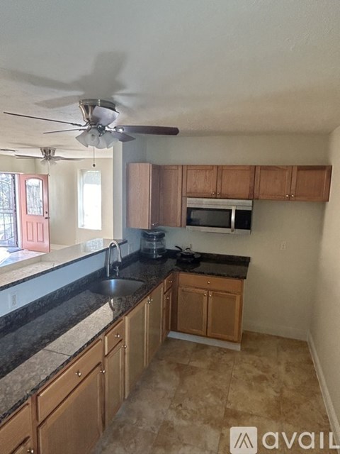A kitchen with wooden cabinets and a black countertop.