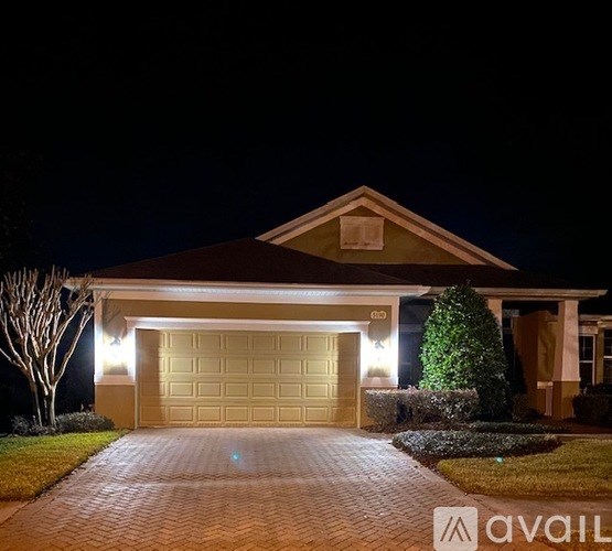 A house with a garage and driveway is lit up at night.