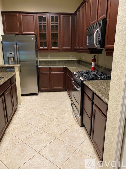A kitchen with brown cabinets and a black microwave above the stove.