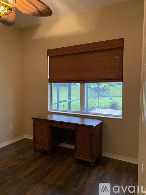 A room with a desk and a window with blinds.