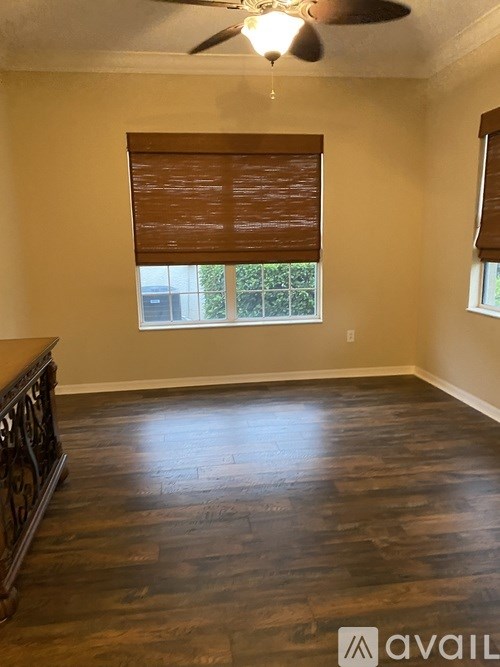 A room with wooden floors and a window with blinds.