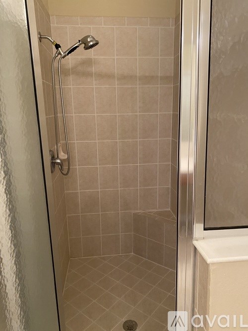 A shower area with a glass door and a tiled wall.