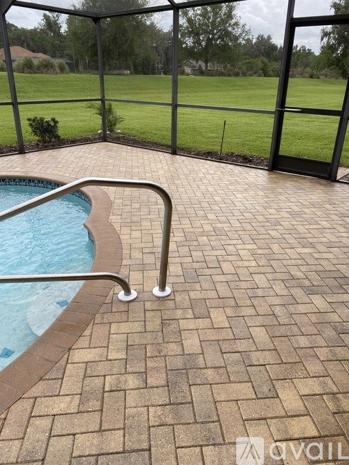 A pool with a brick patterned floor and a glass wall.