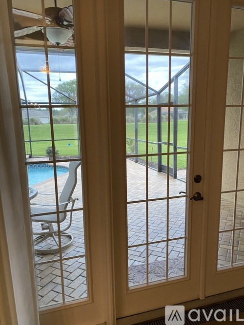 A glass door with a view of a pool and a lawn.