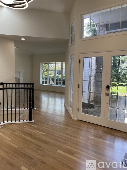A large, empty room with wooden floors and a black railing.