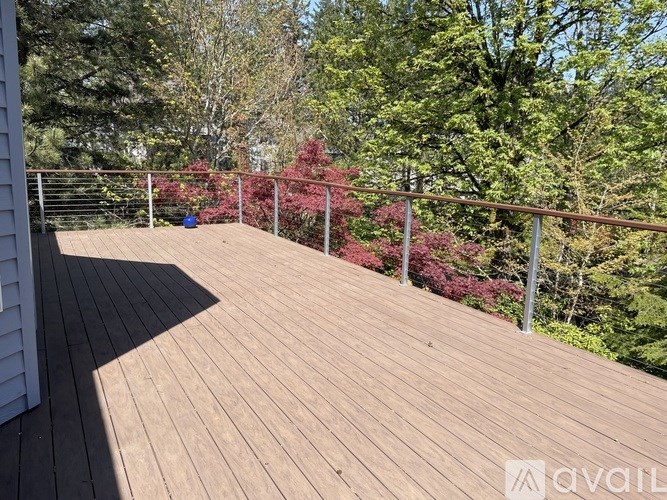 A wooden deck with a railing and trees in the background.