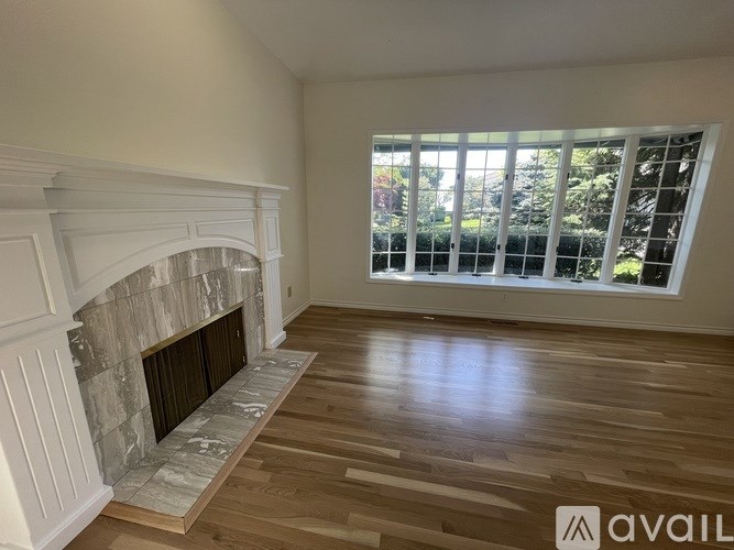 A room with a stone fireplace and wooden flooring.
