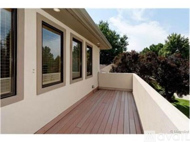 A balcony with a wooden floor and three windows.