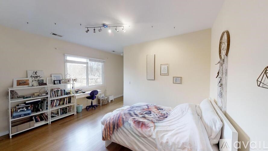 A bedroom with a bed, desk, and bookshelf.