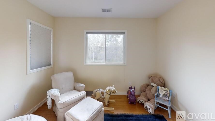 A living room with a white chair, a white sofa, a white teddy bear, a white vase, a white lamp, a white wall, a white ceiling, a white window, a white door, a white floor, a