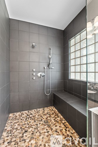 A shower area with a glass door and a stone floor.