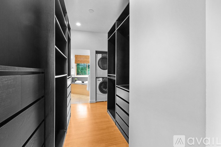 A long hallway with a washer and dryer in the background.