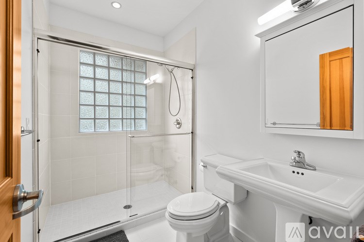 A white bathroom with a toilet, sink, and shower.