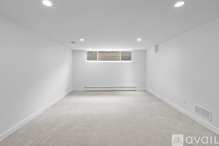 A spacious empty room with a window and carpeted floor.