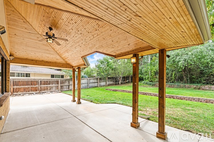 A wooden covered patio area with a ceiling fan.