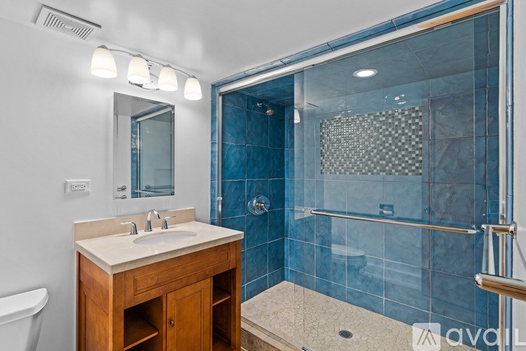 A bathroom with a sink, mirror, and shower.