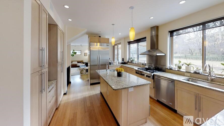 A modern kitchen with wooden floors and stainless steel appliances.