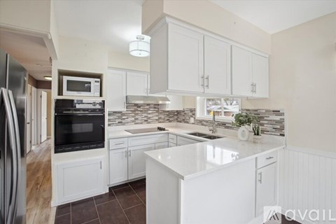 A kitchen with white cabinets and a stone backsplash.