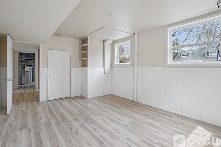 A spacious room with white walls and wooden flooring.