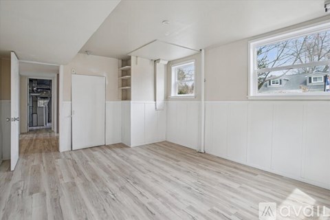 A spacious room with white walls and wooden flooring.