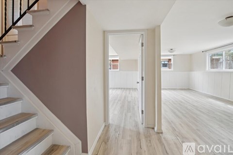 A hallway with a staircase on the left and a doorway leading to another room on the right.