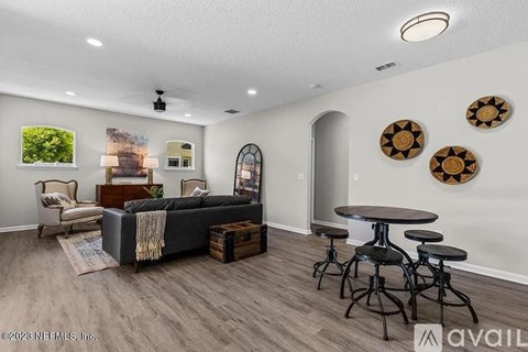 A living room with a grey sofa, a wooden coffee table, and a round table with stools.