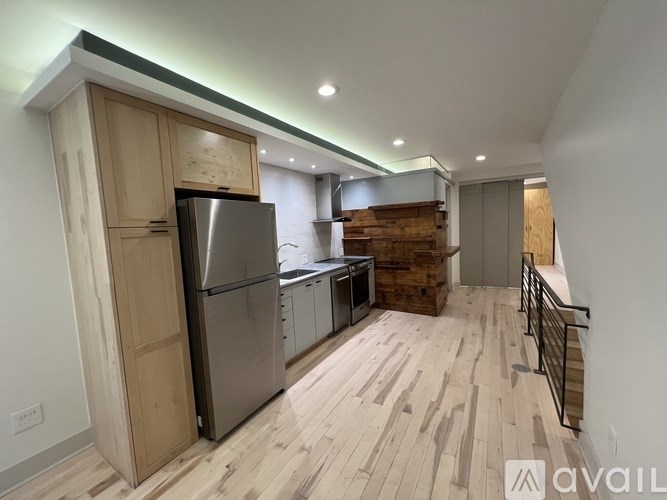 A kitchen with wooden floors and a stainless steel refrigerator.