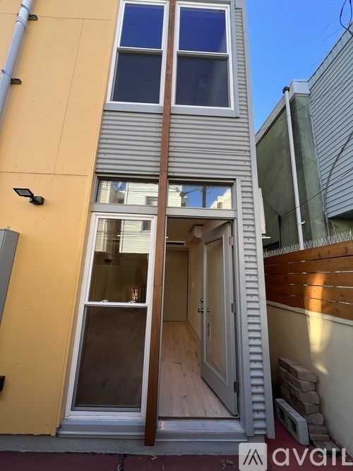 A yellow building with a window and a door open.