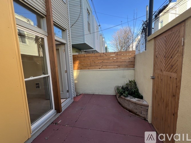 A small patio area with a wooden door and a brick wall.