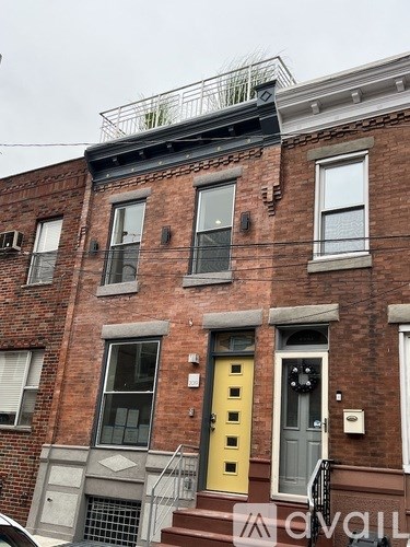 A red brick building with a yellow door and a balcony on the second floor.