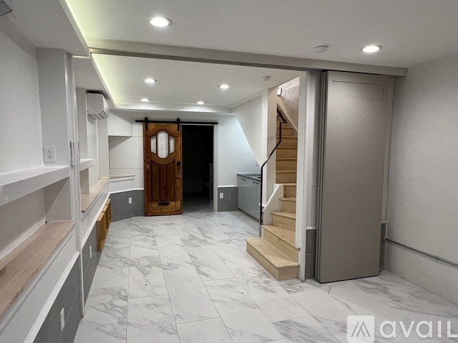 A spacious hallway with marble flooring and a staircase leading to another room.