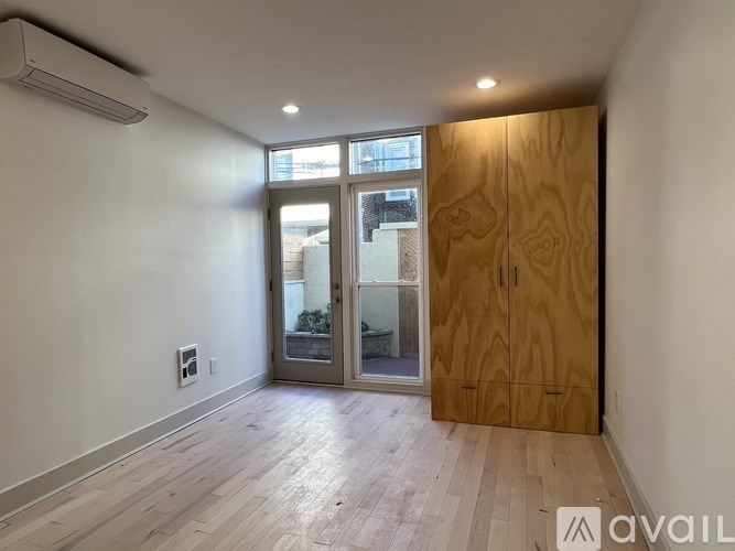 A room with a wooden door and a window with a view of a balcony.