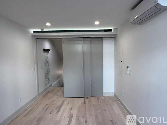 A room with a wooden floor and a wall-mounted air conditioner.