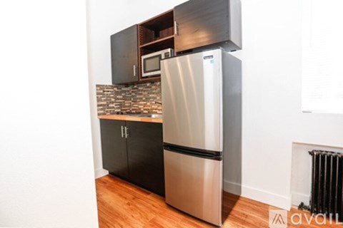 A kitchen with a stainless steel refrigerator and black cabinets.