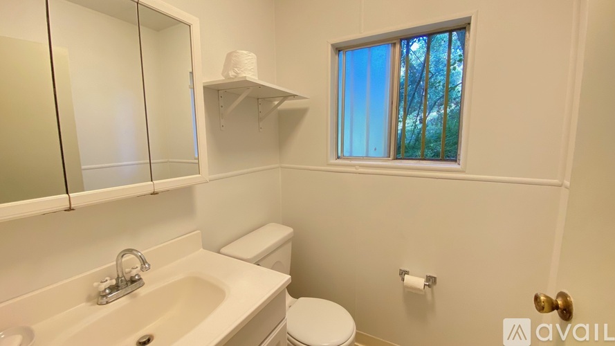 A bathroom with a toilet, sink, and a window.