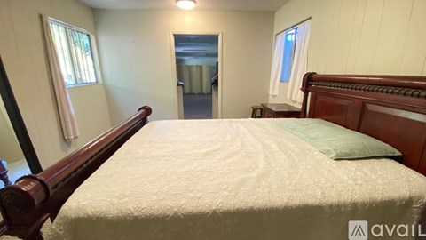 A bedroom with a large bed and a window with curtains.