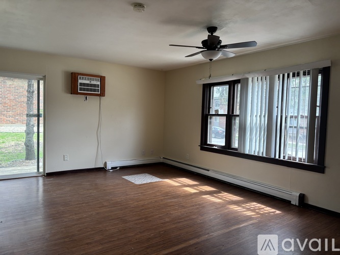 A room with a ceiling fan and a window with blinds.