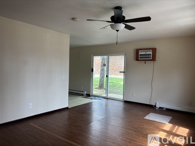 A room with a ceiling fan and sliding glass doors leading to a backyard.