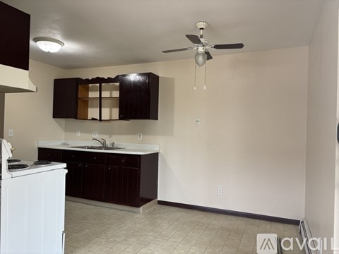 A kitchen with a white dishwasher and dark brown cabinets.