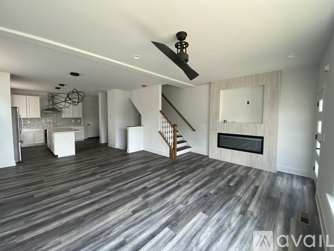 A spacious living room with wood flooring and a staircase leading to the upper level.