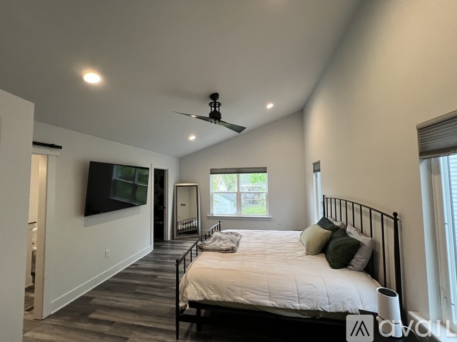 A bedroom with a bed, a television, and a window.