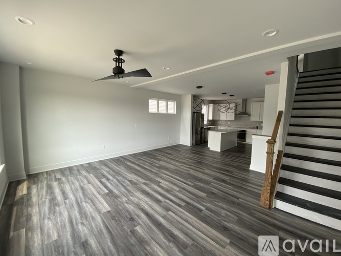 A spacious room with wooden flooring and a ceiling fan.
