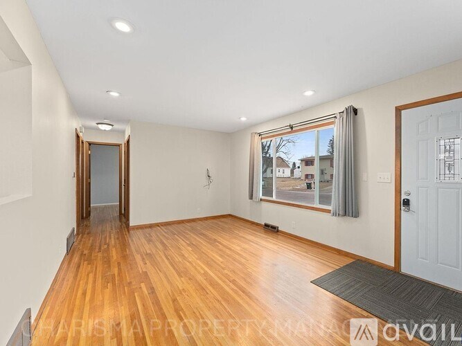 A spacious room with wooden floors and a large window with a view of the outside.