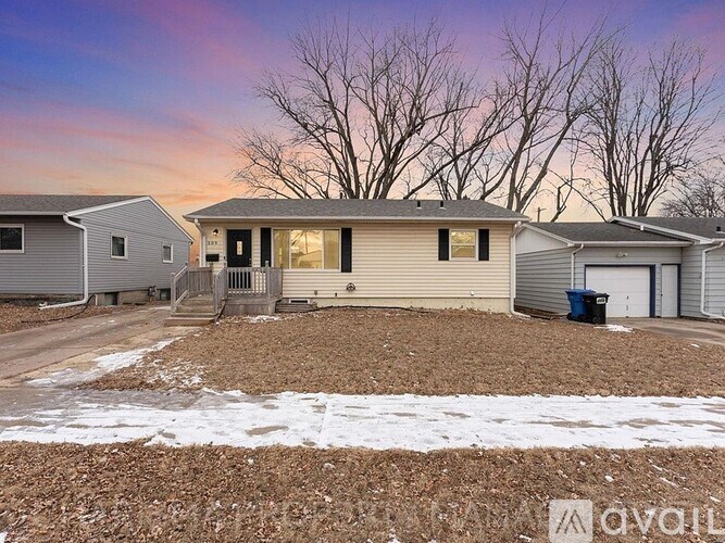 A house with a driveway and a trash can in front of it.