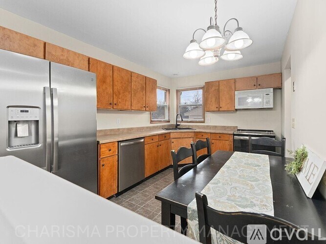 A kitchen with a refrigerator, microwave, and a dining table with chairs.