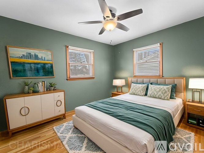 A bedroom with a bed, a dresser, and a ceiling fan.