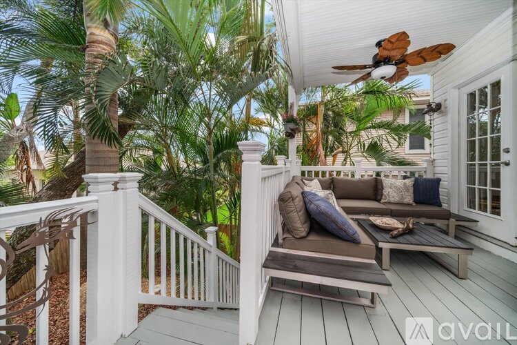 A white deck with a couch and pillows, surrounded by trees.