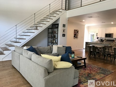 A living room with a grey couch and a staircase.